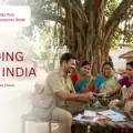 A postman providing doorstep banking services to a women's Self Help Group using IPPB technology.