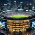 Modern football stadium illuminated at night with a global sports business atmosphere representing the commercialization of elite football clubs.