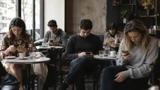 People sitting together in a café while individually focused on smartphones instead of real conversation.