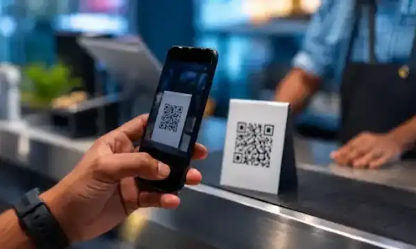 Smartphone scanning a QR code representing digital payments and online security awareness.