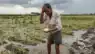 Candid smartphone photo of a distressed farmer inspecting crop damage from unseasonal rain and hailstorm near Chhatrapati Sambhajinagar, Maharashtra.