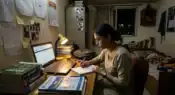 Indian college student studying late at night while managing scholarship applications and financial pressure inside a university hostel room.