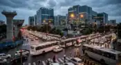 A busy corporate transit corridor in Pune showing a long line of company buses and vehicles moving slowly past an under-construction metro pillar representative image.