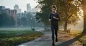 Young professional jogging in an urban park at sunrise while trying to improve fitness and health in modern city life.