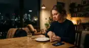 Young office worker feeling hungry late at night despite recently eating dinner in a modern urban apartment representative image.