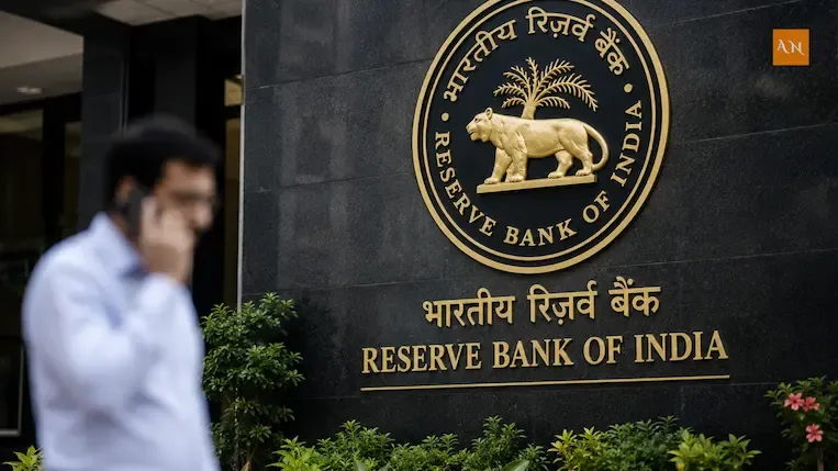 Reserve Bank of India logo on building wall with blurred man talking on phone, finance news concept.